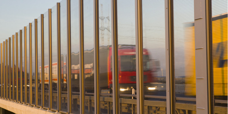 Lkws fahren auf der Autobahn hinter einer Lärmschutzwand.