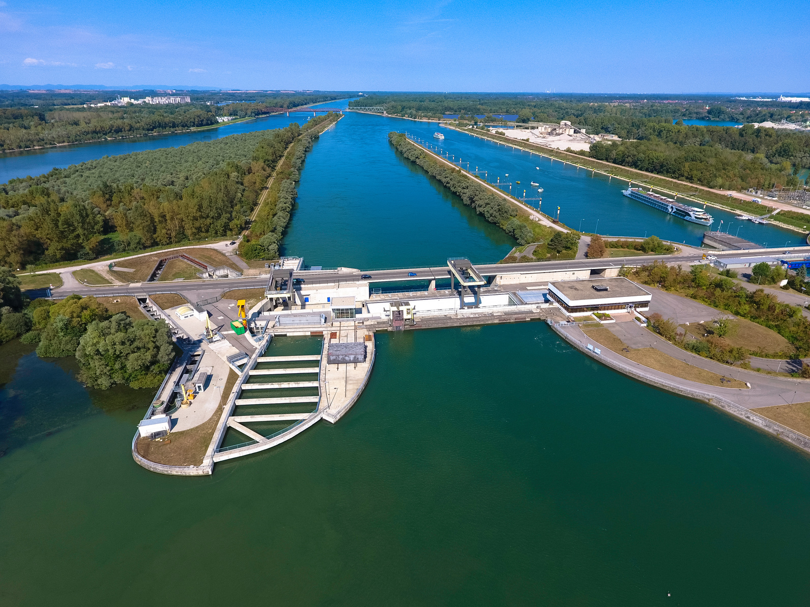 Foto: Das Wasserkraftwerk Iffezheim samt Staustufe am stark ausgebauten und begradigten Rhein. Im Vordergrund ist ein großer Fischpass zu sehen.