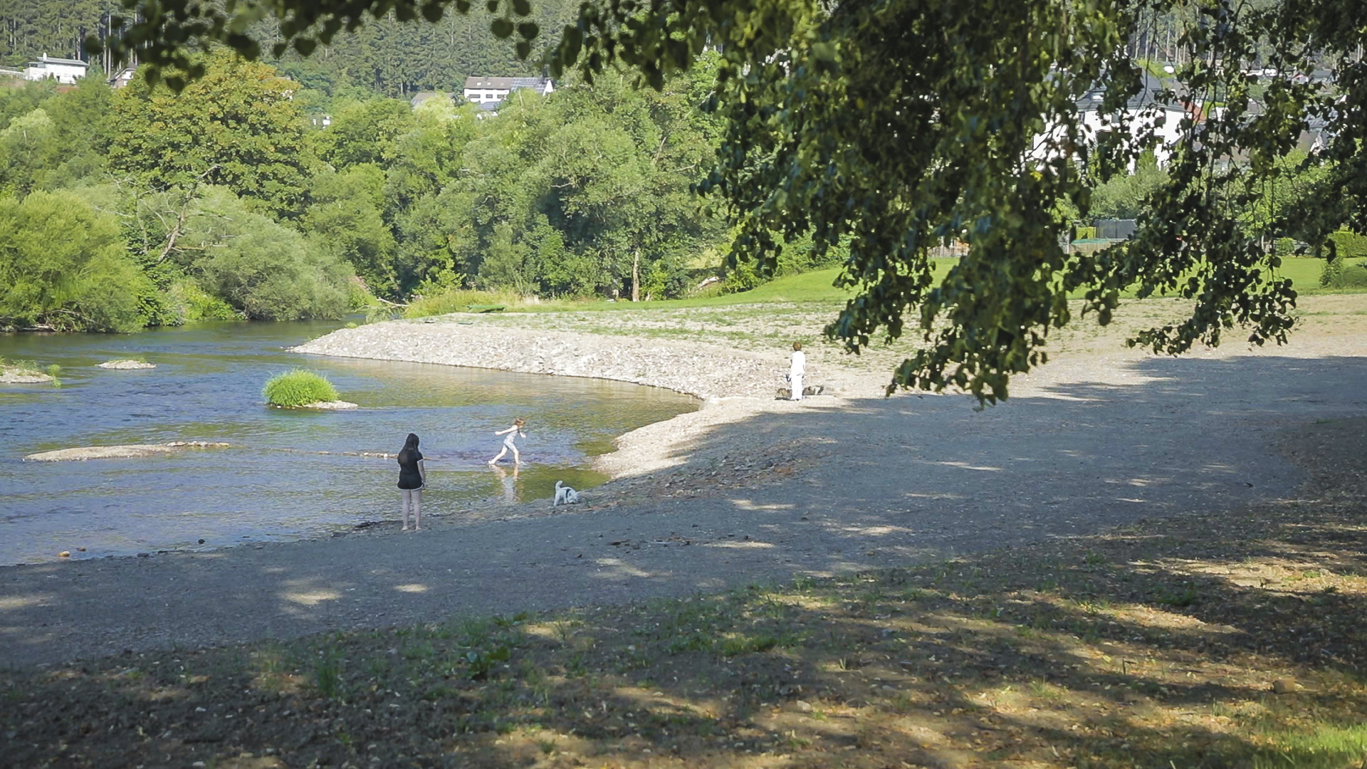 Foto: Erholungssuchende Menschen an der renaturierten Ruhr in Oeventrop. Im Gewässer befinden sich kleine Kiesbänke. Im Hintergrund wächst üppige Vegetation entlang der Ufer.