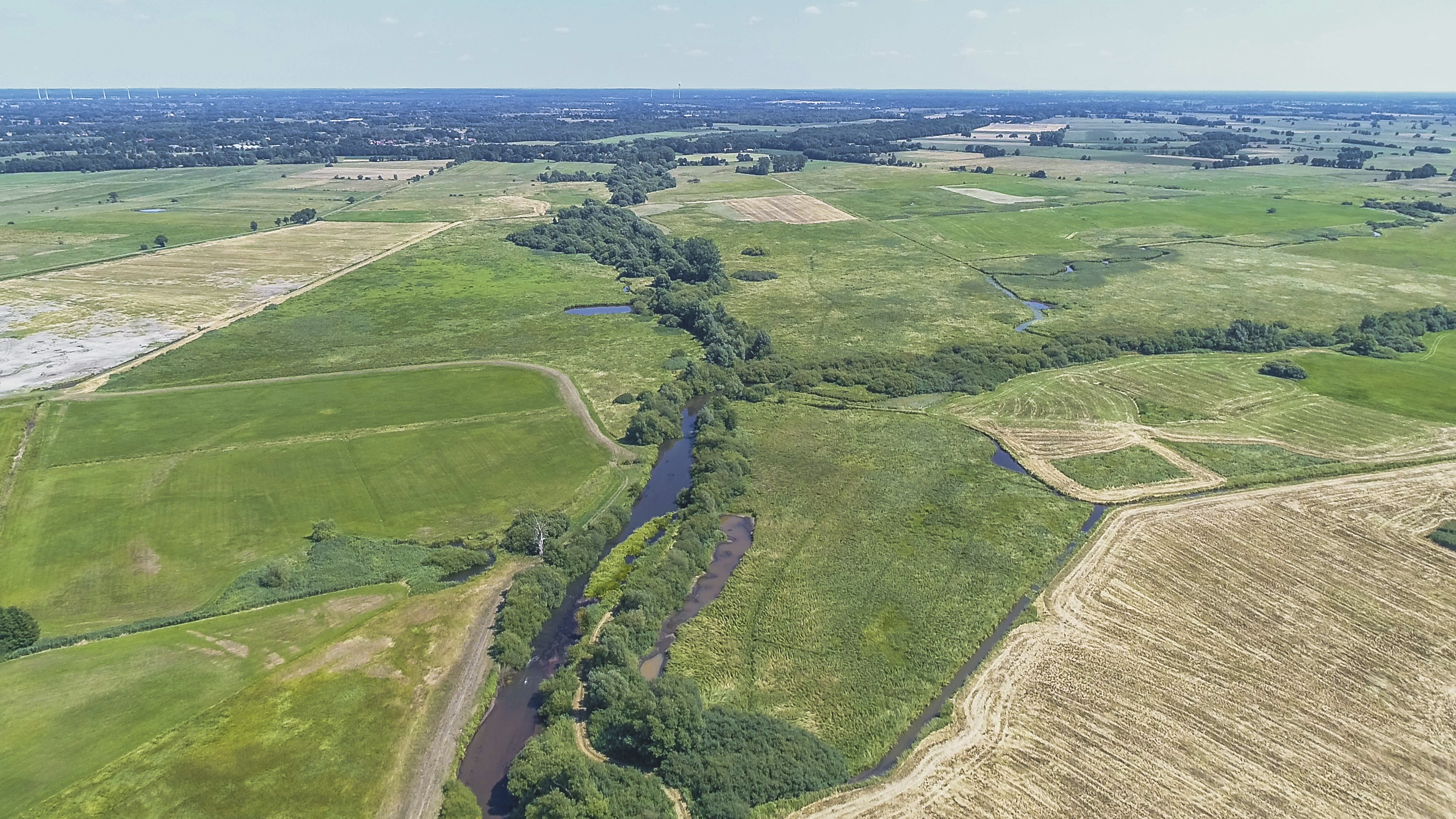 Luftbild der Wümme mit durchgehendem Gehölzsaum umgeben von landwirtschaftlich genutzten Grünlandflächen