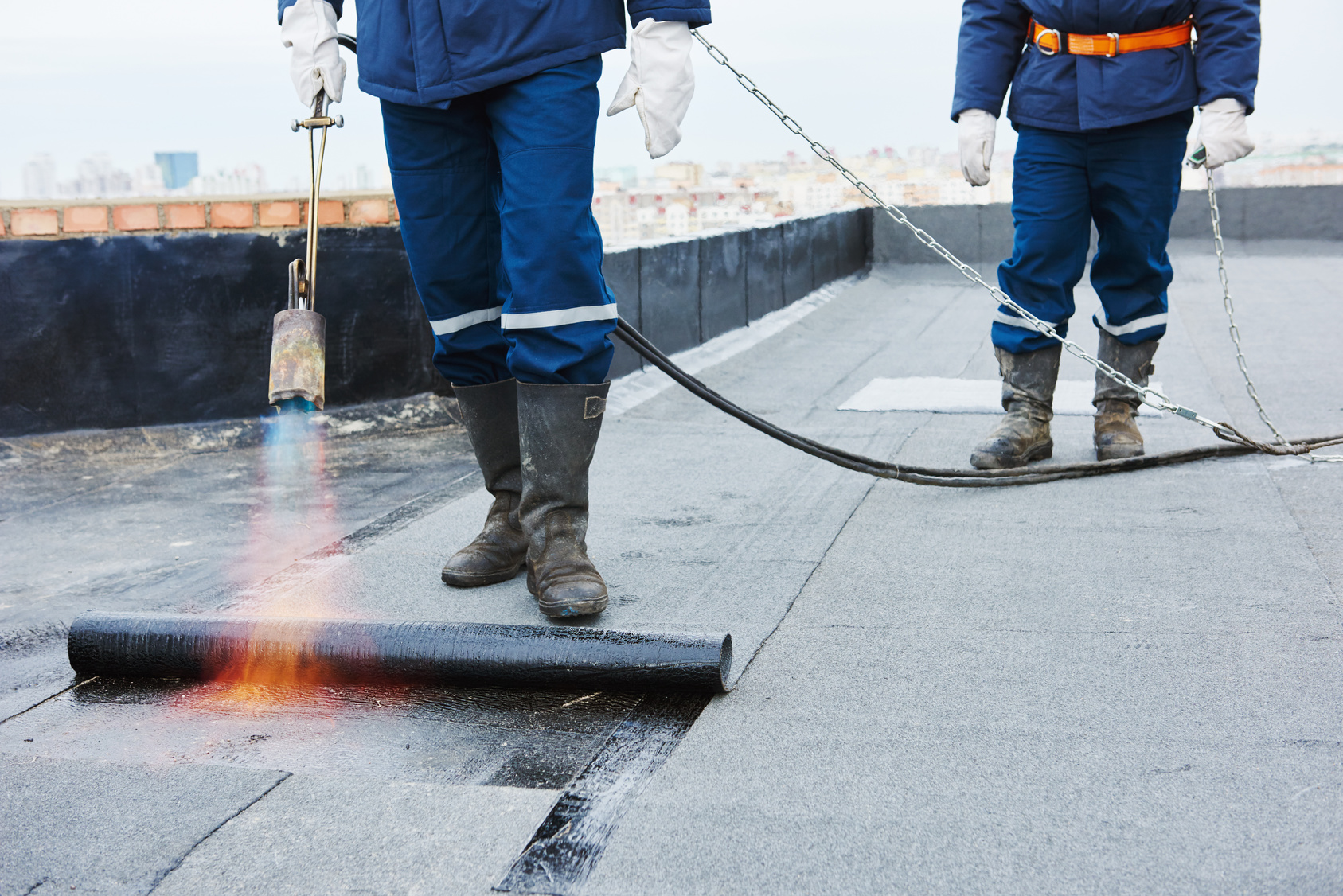 Bauarbeiter verlegen bitumenhaltige Dachbahnen.