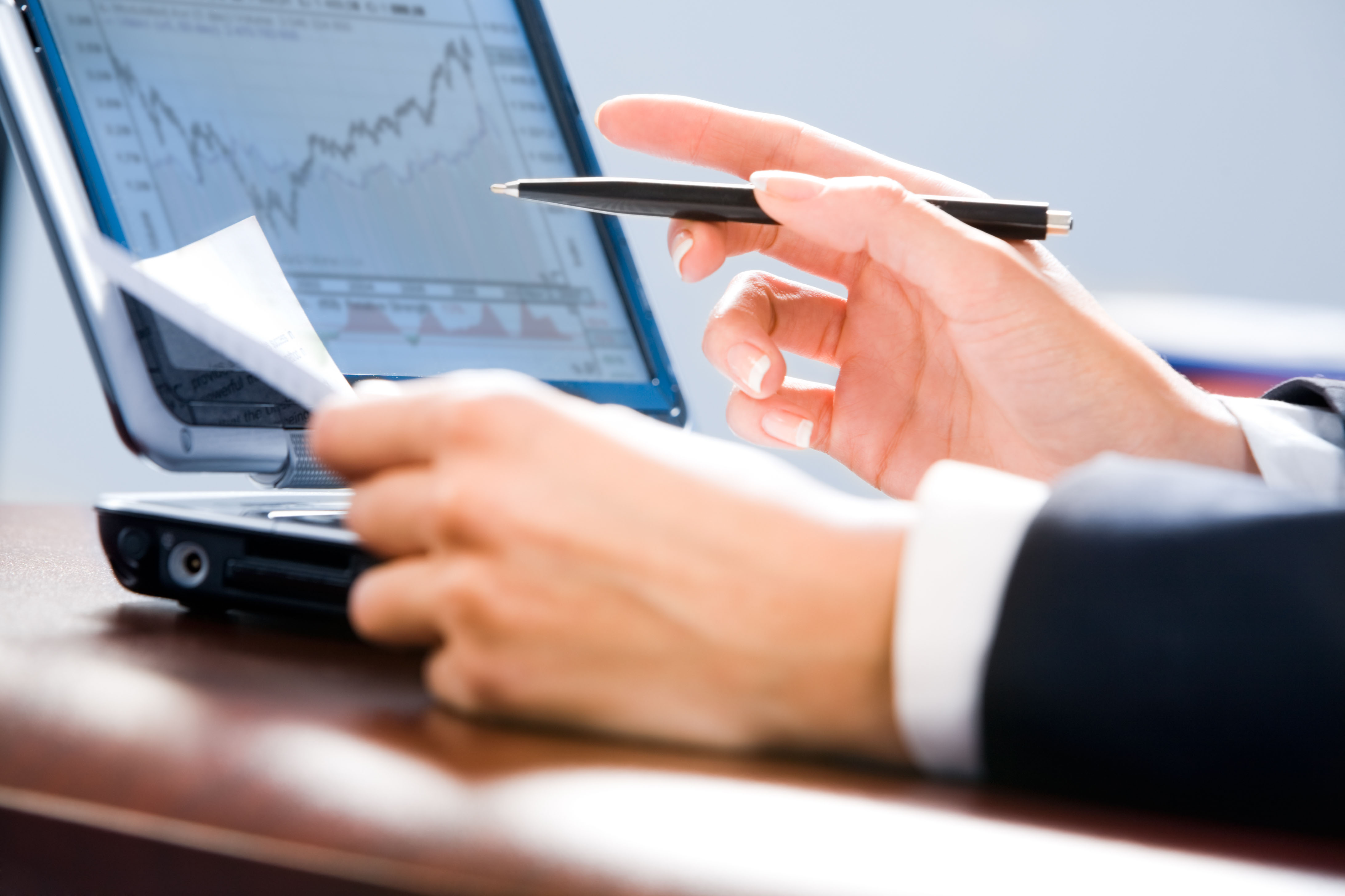 Hands in front of a laptop screen showing a trading picture.