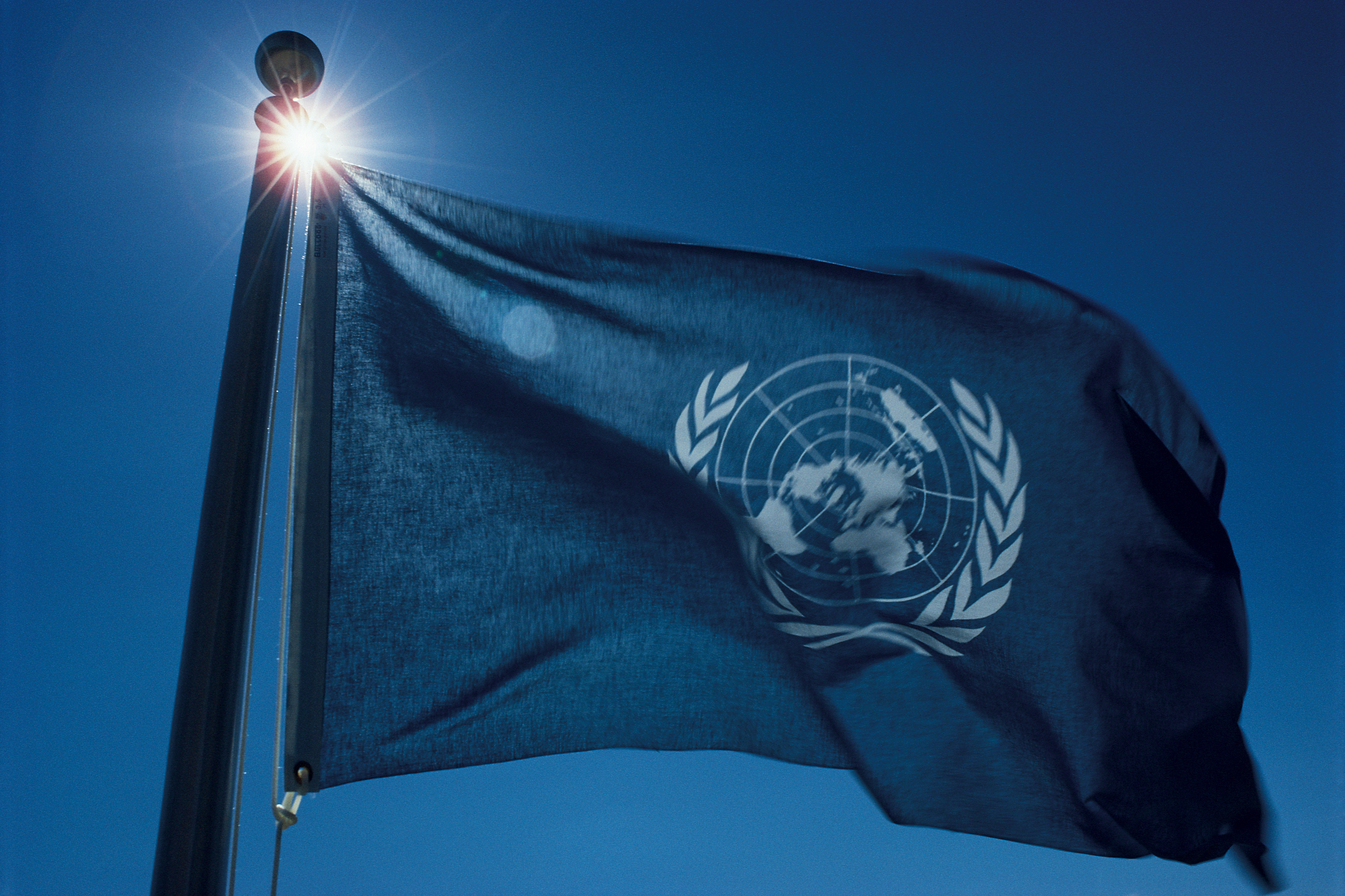 Wehende Flagge der Vereinten Nationen vor blauem Himmel
