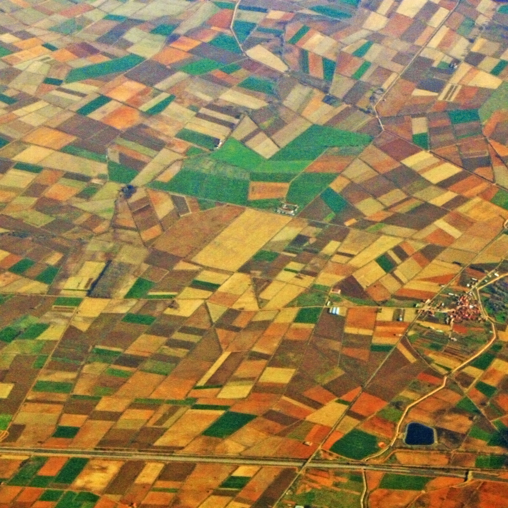 Bird's eye view of geometrical arranged, colourful fields and settlements