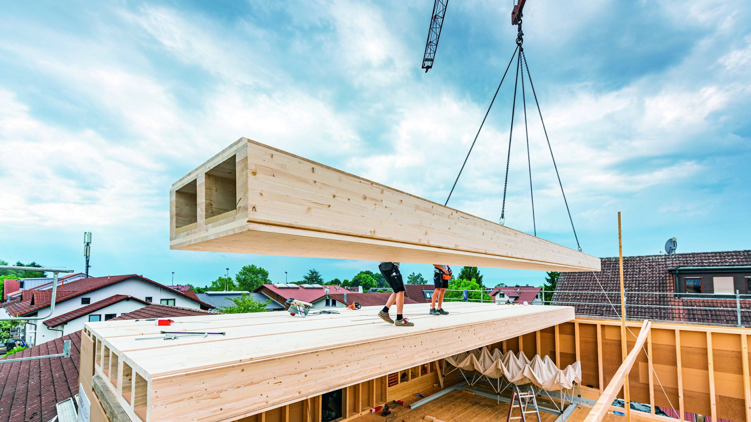 Vorgefertigte Holzelemente werden mit einem Kran als Geschossdecke auf einen Holzbau gesetzt