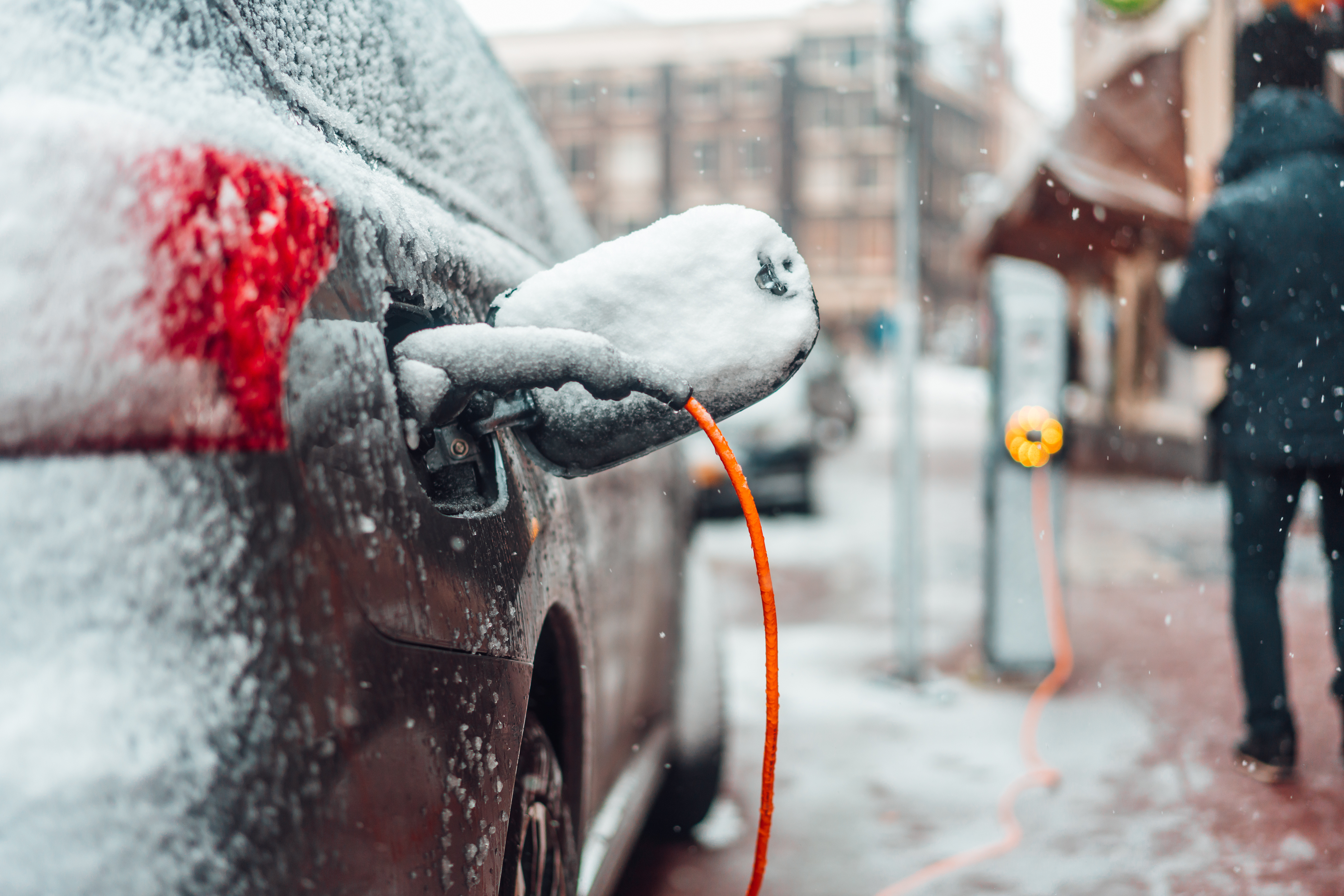 Ein verschneites Elektroauto wird  bei winterlichen Bedingungen geladen.