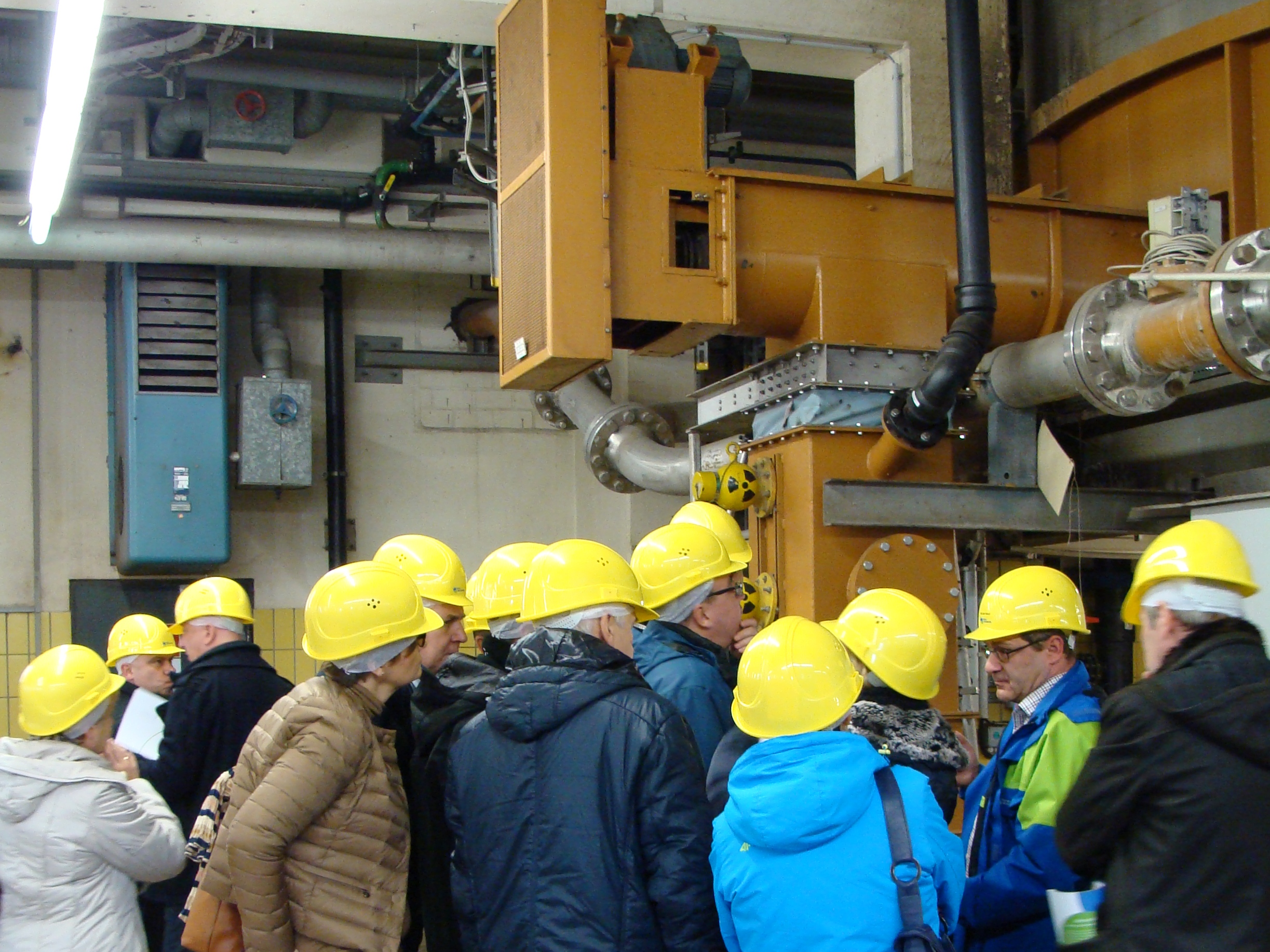 Group of people with yellow hard hats looking at technical installation