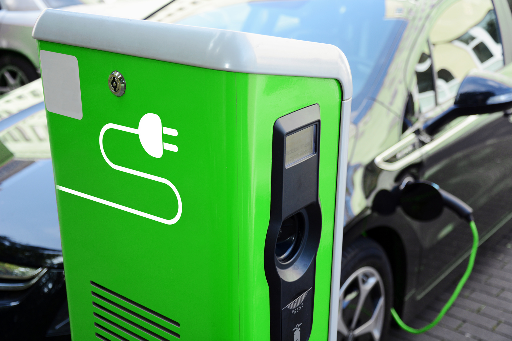 ein Elektroauto tankt Strom an einer grünen Ladesäule