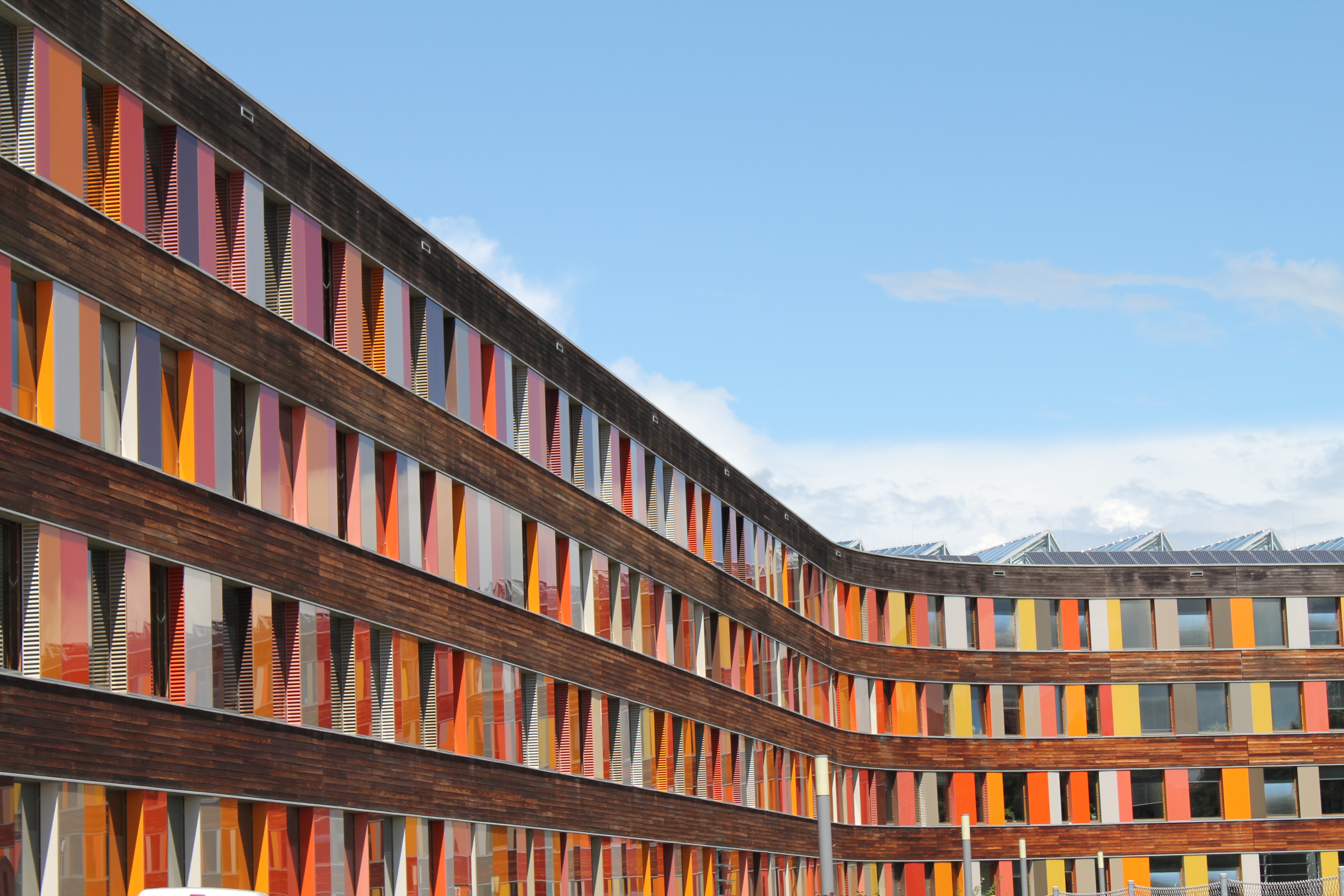 Rückwärtige Holz-Fassade des UBA Dessau-Roßlau mit Glasplatten in verschiedenen Rottönen