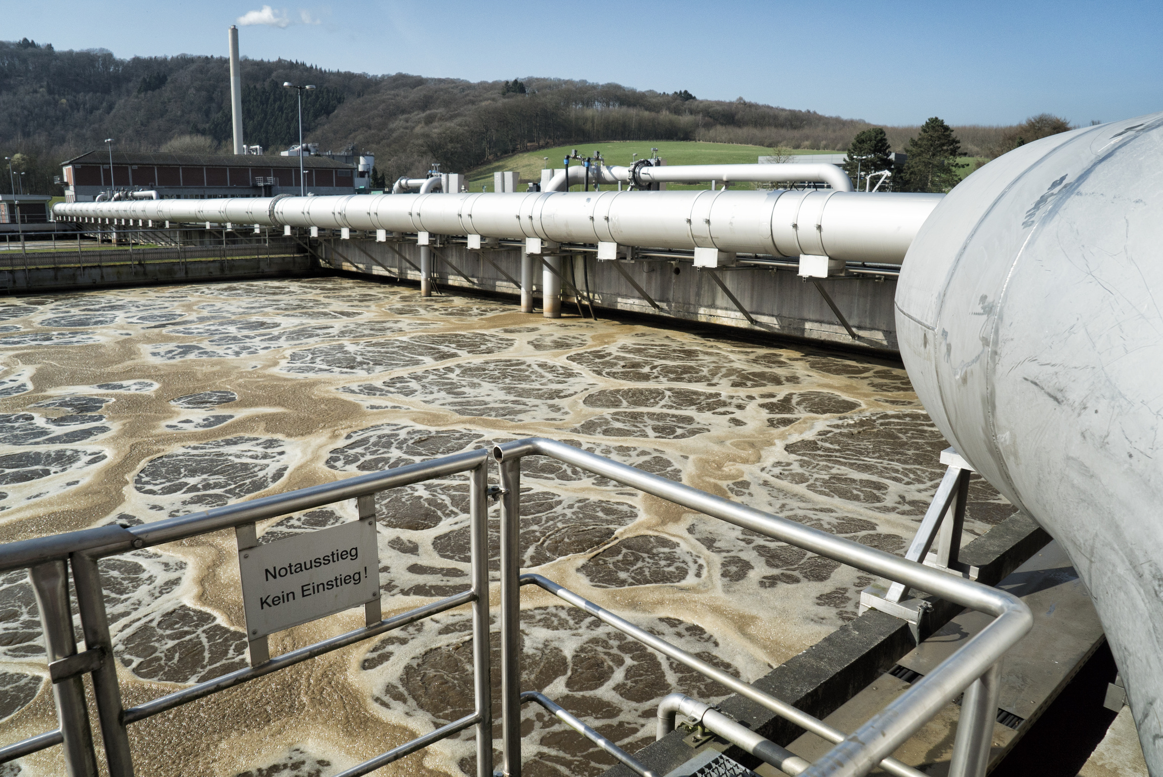 Becken einer Kläranlage mit braunem, schaumigem Wasser