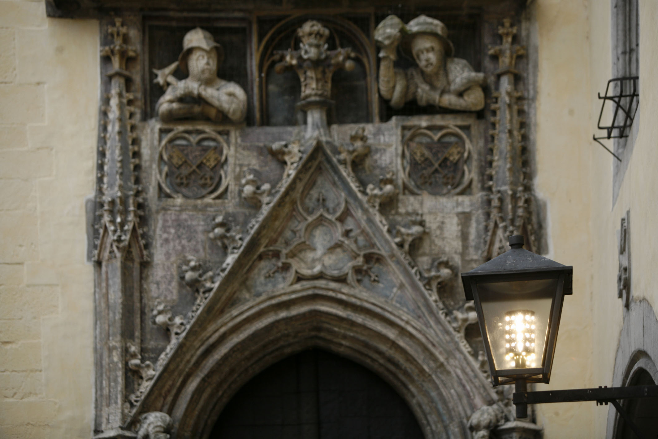 Portal eines alten Bauwerkes mit Figuren, davor eine Straßenlaterne im nostalgisch altem Design, aber mit modernen LED-Lampen