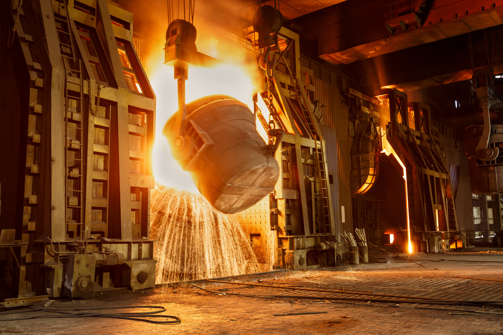 in einer Werkshalle wird ein riesiger Bottich mit glühendheißem, flüssigen Metall ausgekippt