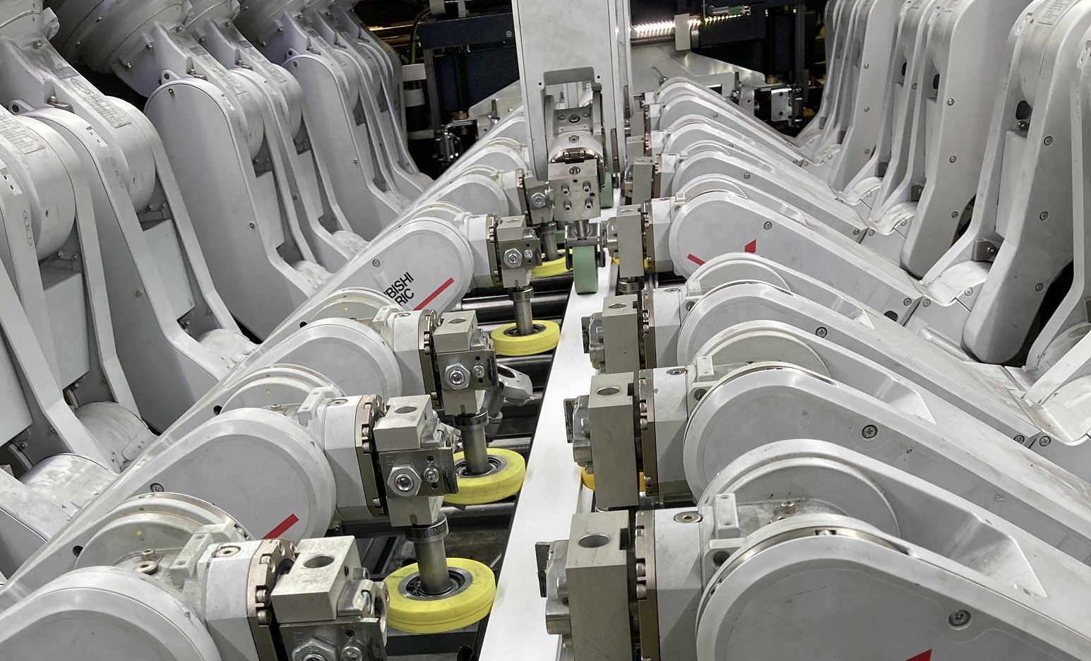 technische Anlage mit 12 Roboterarmen, die eine Folie auf ein PVC-Profil aufbringen