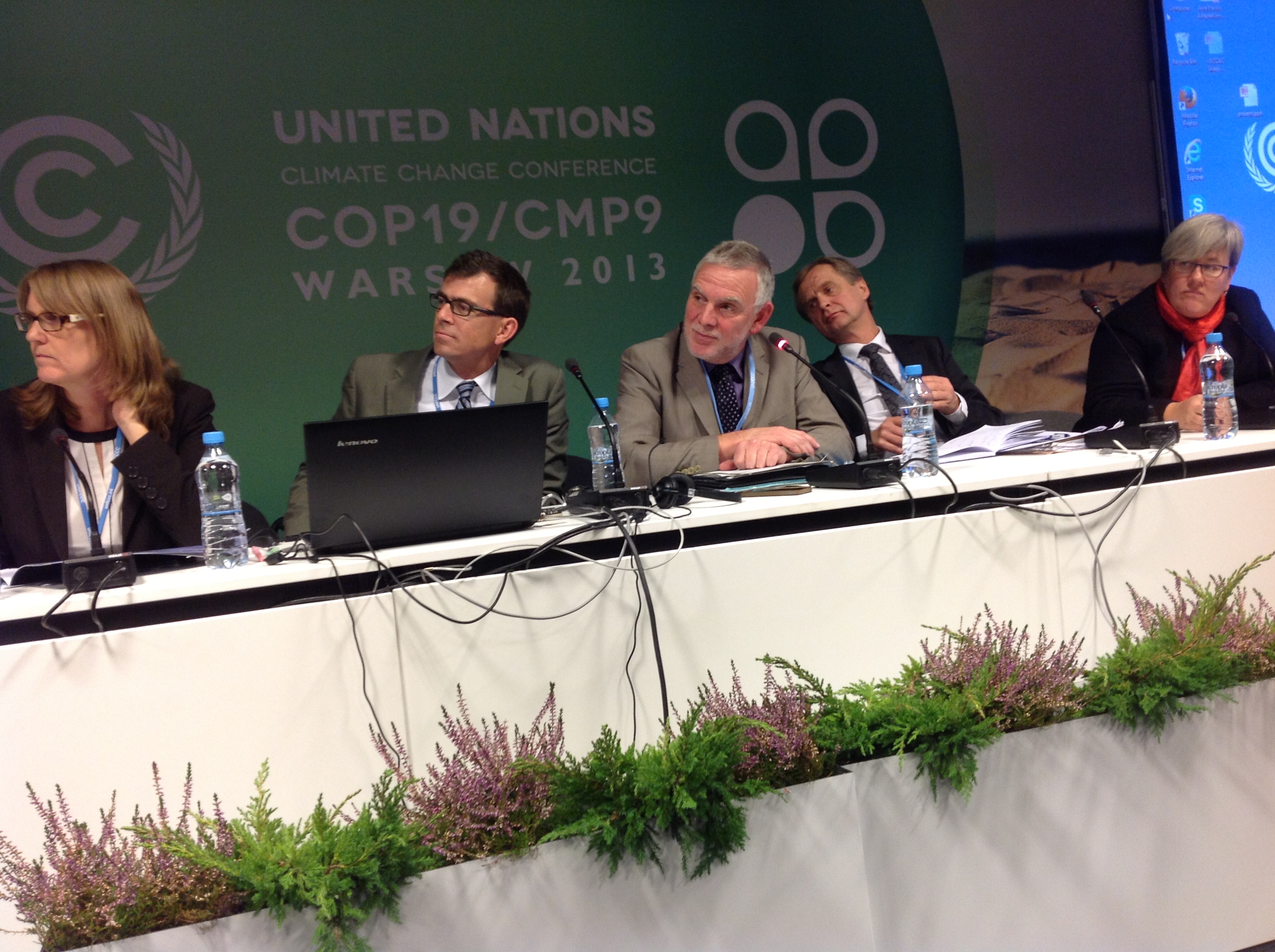 podium with 5 speakers, in the background the logo of the world climate change summit in Warsaw