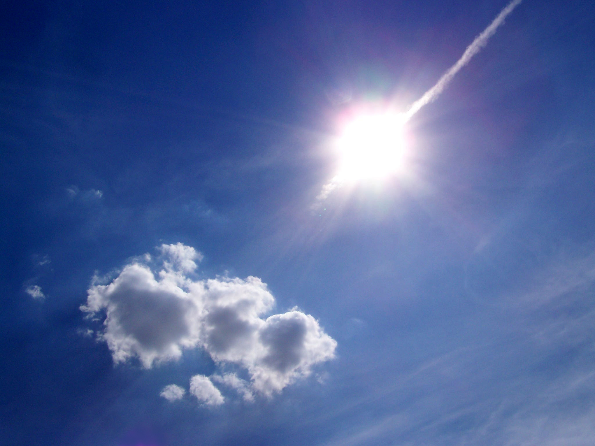 strahlende Sonne an einem blauen Himmel mit Schönwetterwolke