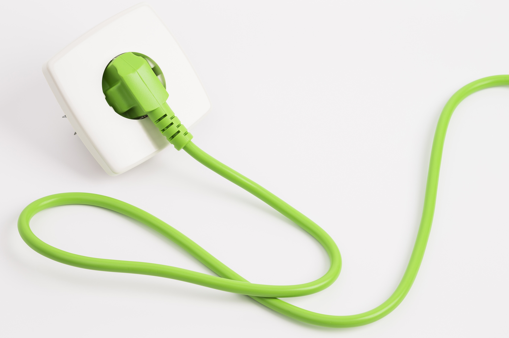 ein grüner Stecker mit grünem Stromkabel steckt in einer Steckdose