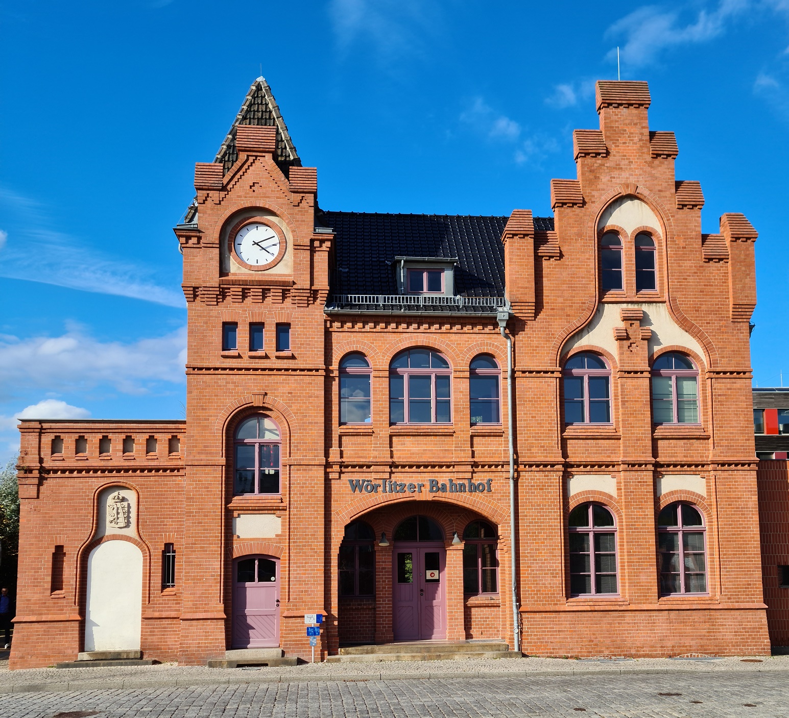 kleines, altes Bahnhofsgebäude aus rotem Backstein, über der Eingangstür der Schriftzug "Wörlitzer Bahnhof"