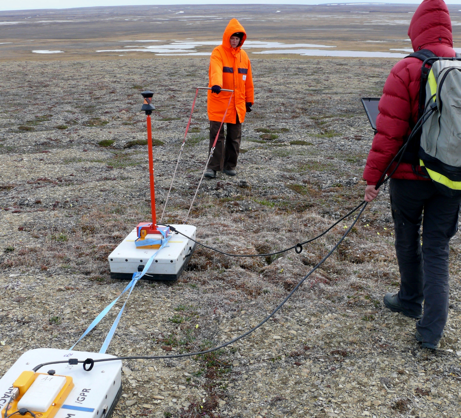 Zwei Forscherinnen stehen mit ihren Instrumenten in der arktischen Landschaft.