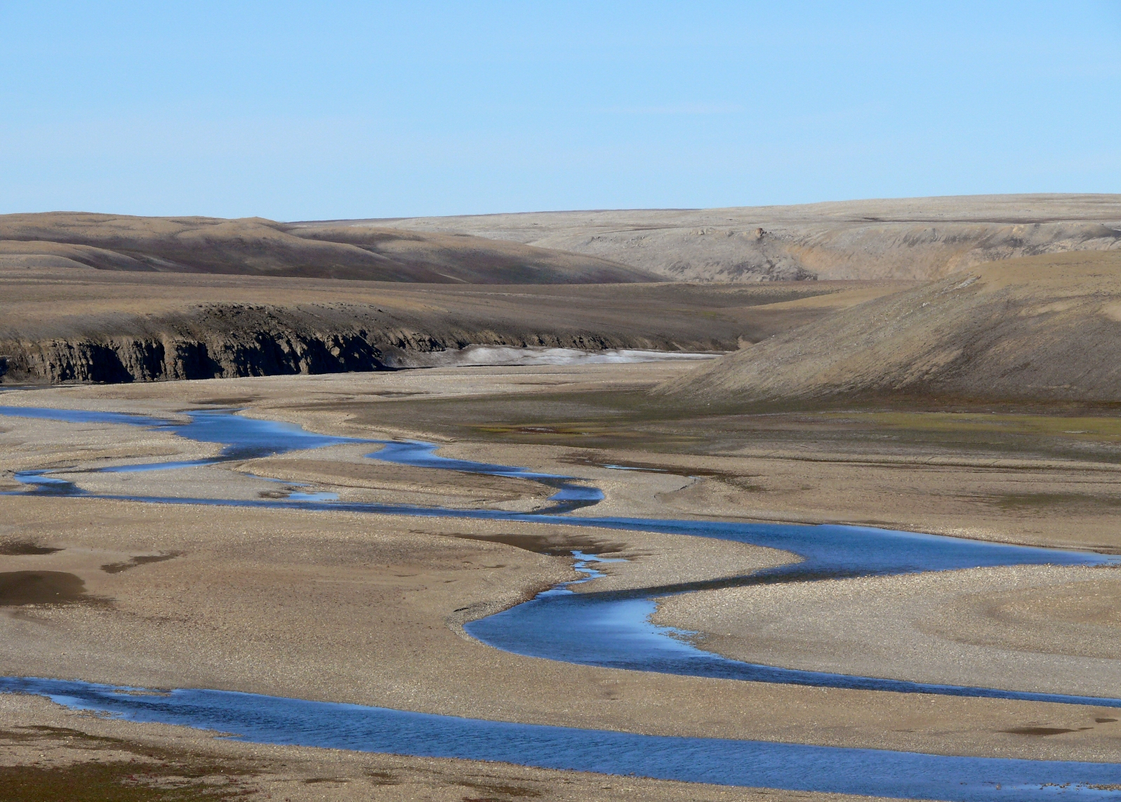 Ein Fluss schlängelt sich durch die karge arktische Landschaft.