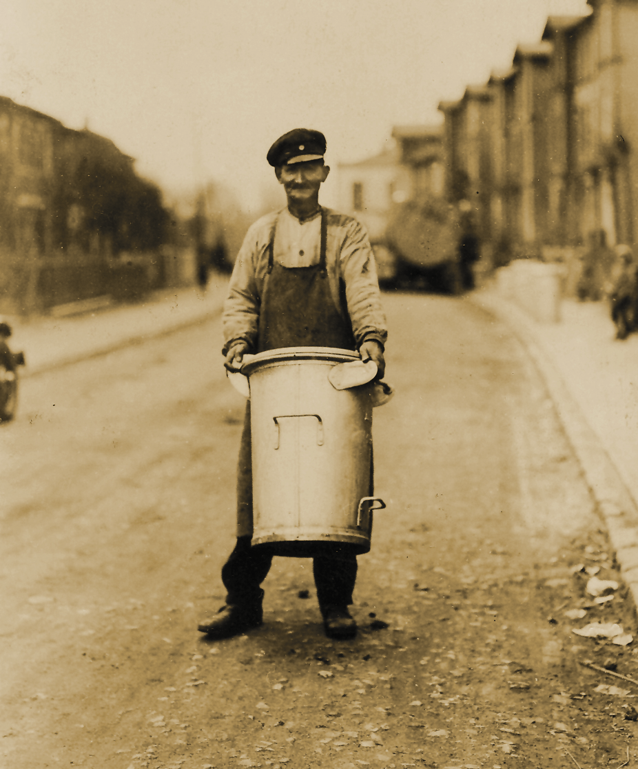 Ein Mann trägt eine hohe Mülltonne auf der Straße