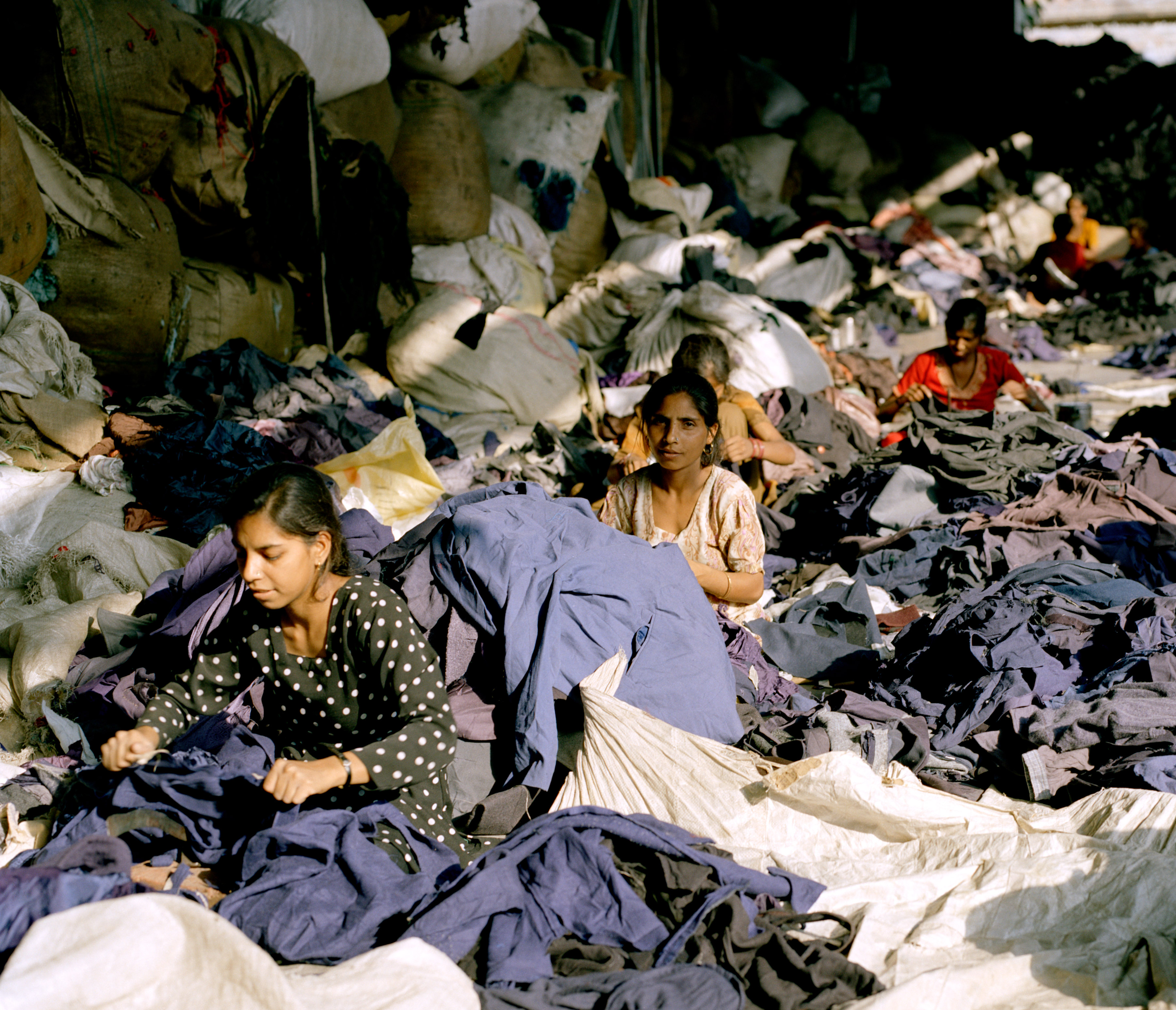 Frauen zerschneiden Jacken und Oberteile; die eingenähten Etiketten werden herausgeschnitten - Marken und Labelsangaben werden bei dem Prozess wertlos.