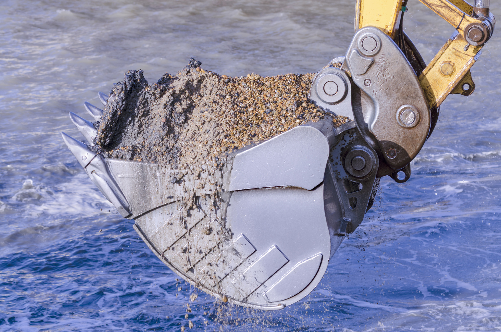 Excavator bucket with sediment in a river
