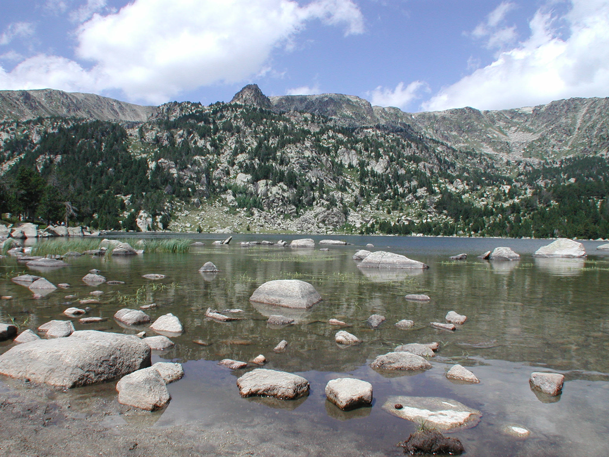 Ein See umgeben von Bergen mit klarem Wasser