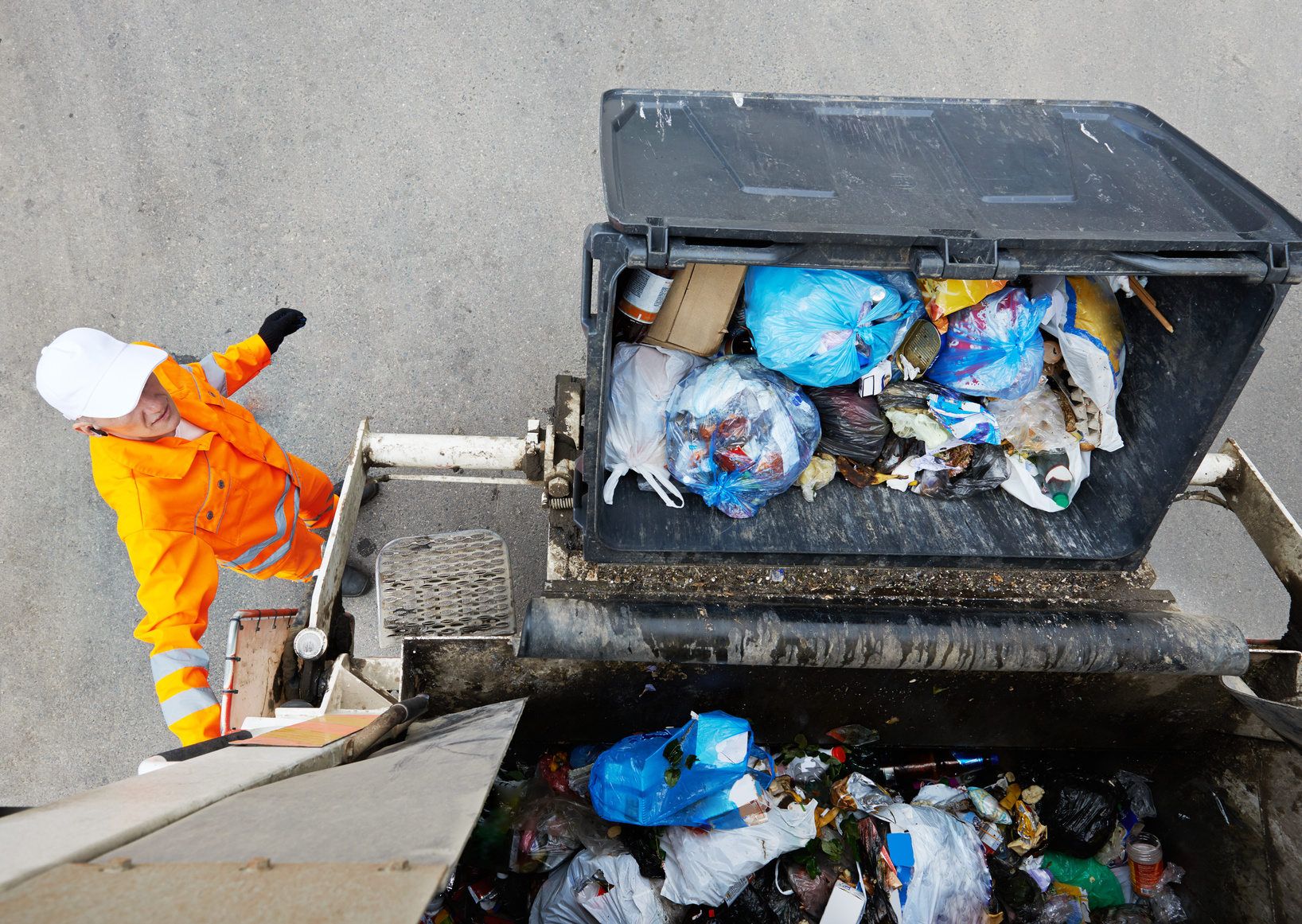 Ein Müllcontainer wird in einen Müllwagen gekippt.