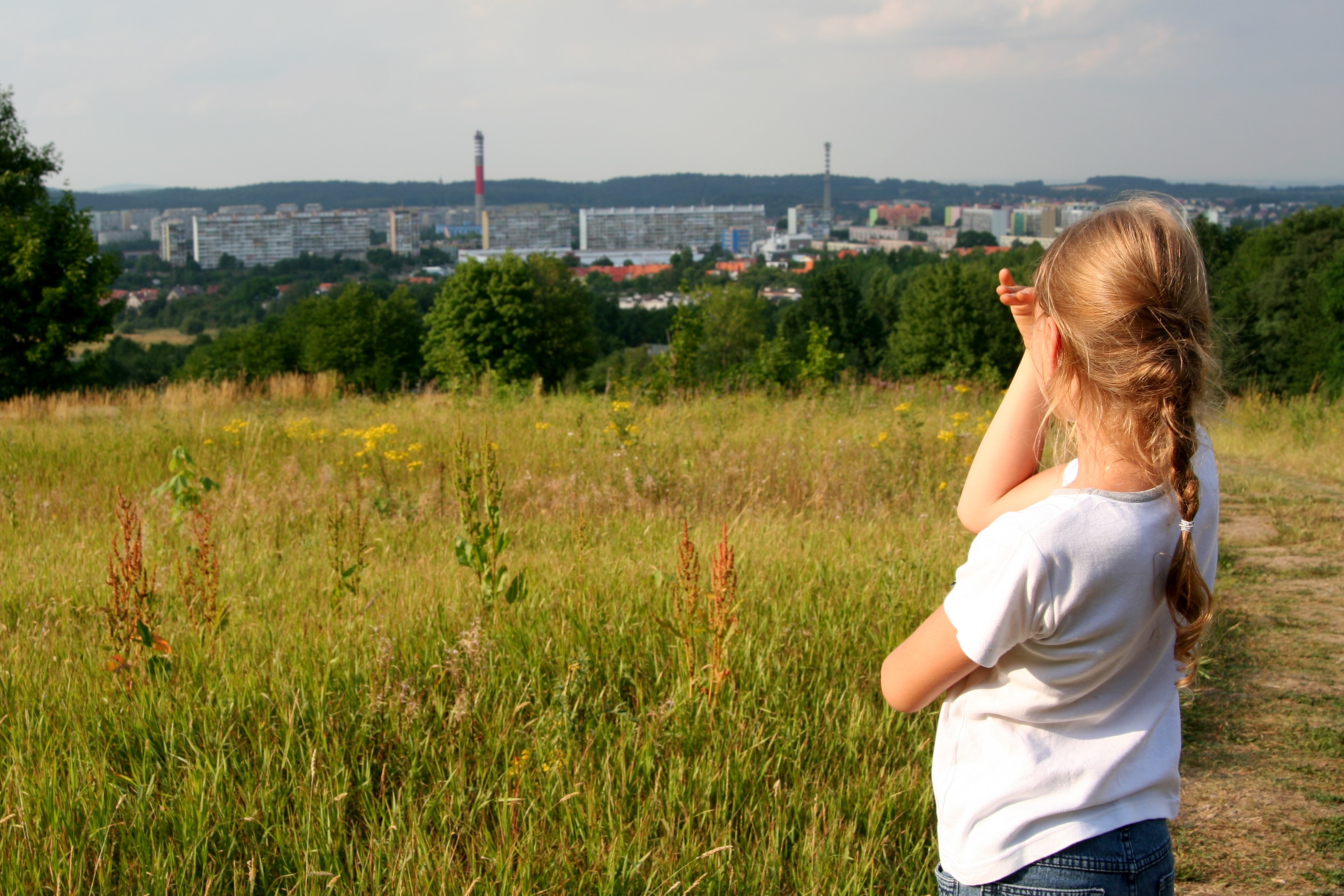 Kind auf einem Feld schau auf die entfernte Stadt.