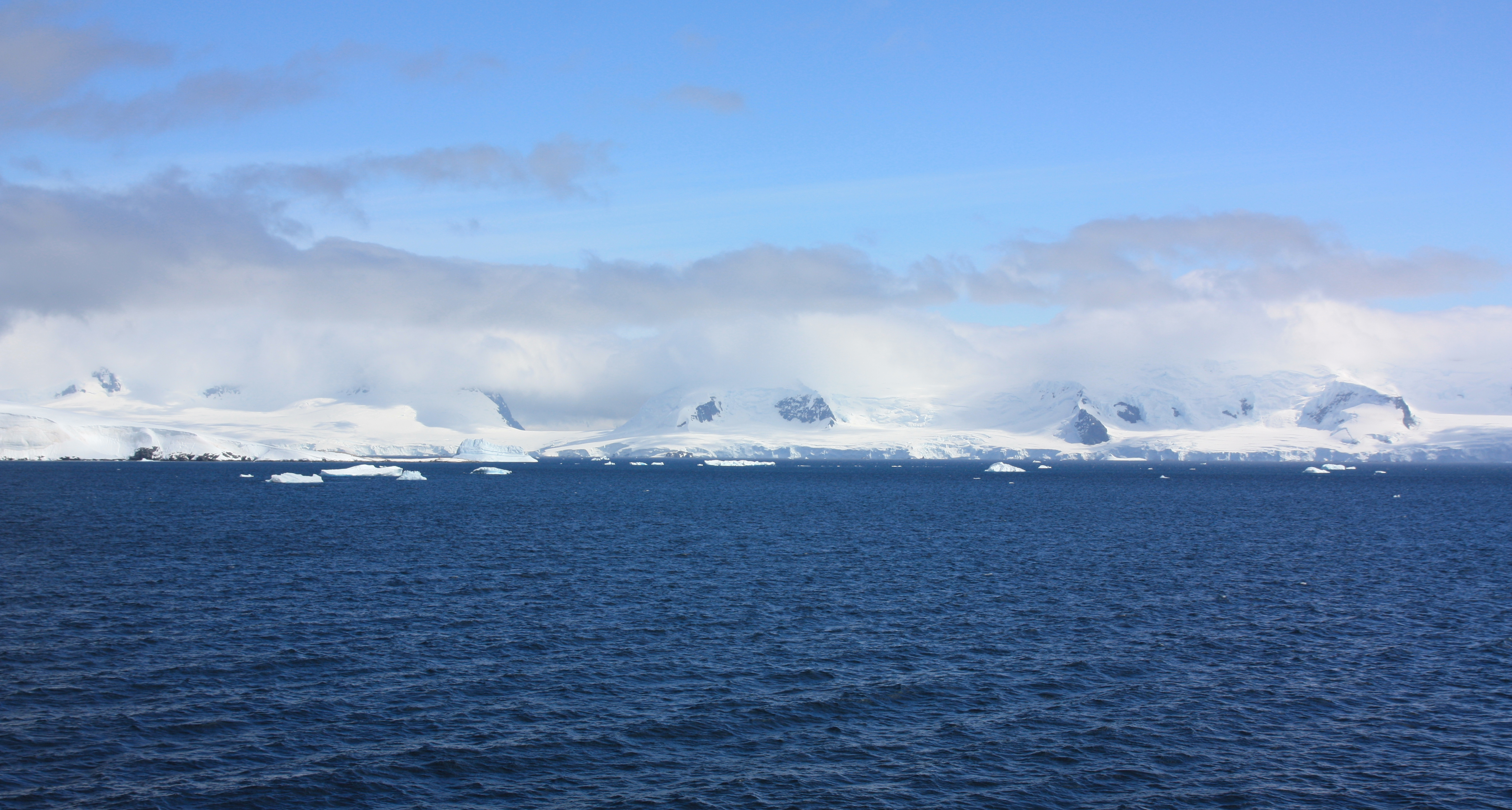 Two layers of clouds envelop mountains in the Antarctic.