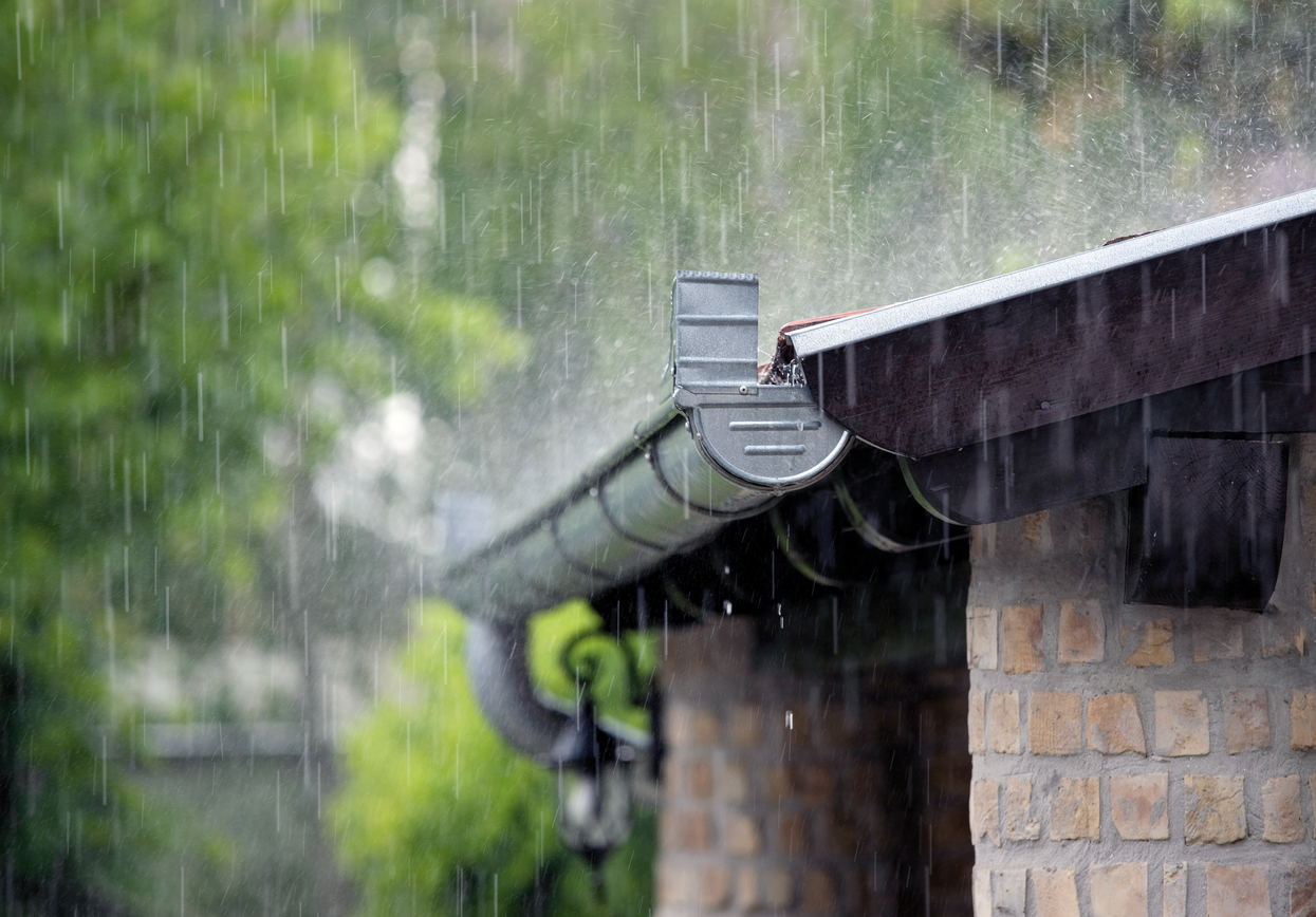 The picture shows the rainwater gutter of a brick building. Heavy rain is falling.