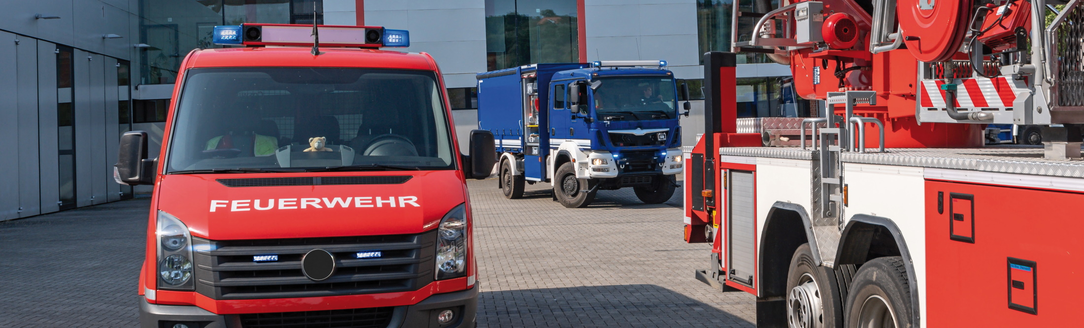 Das Bild zeigt zwei Einsatzfahrzeuge mit angeschaltetem Blaulicht, ein rotes der Feuerwehr und ein blaues des Technischen Hilfswerks. Beide Fahrzeuge sind nur in Teilen zu sehen.
