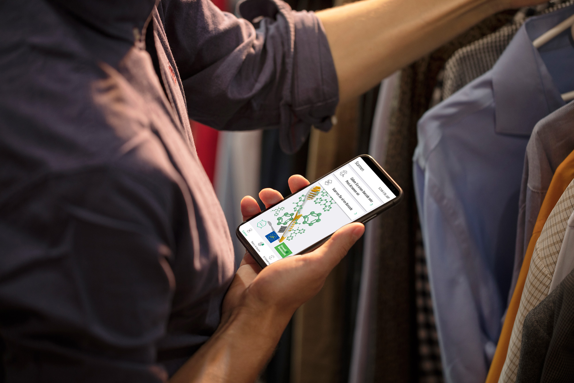 Eine Person mit einem Handy in der Hand. Zu sehen ist die App Scan4Chem auf dem Screen, mit der Barcodes gescannt werden können. 