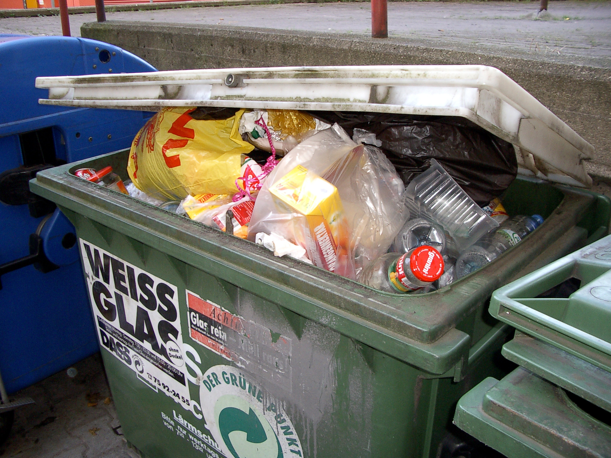 Glass container contains white glass bottles, but also plastic waste