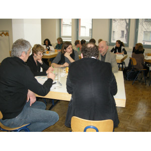 Die Workshopteilnehmer sitzen in kleinen Runden um Tische zusammen und diskutieren. 
