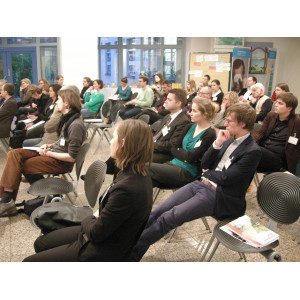 Die Workshopteilnehmer sitzen in Stuhlreihen und hören gebannt den Ausführungen der Vortragenden zu.