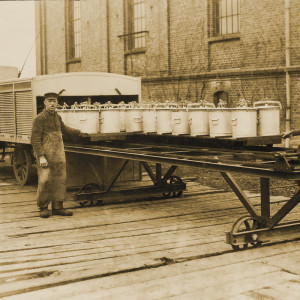 Zwei Männer tauschen Eimer auf einem auf Schienen laufenden Wagen aus.
