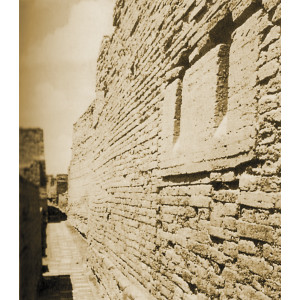 Abschüssige Auslassungen in der Mauer eines antiken Steinhauses durch die Müll aus dem Gebäude in Tongefäße auf der Straße darunter entsorgt wurde. 