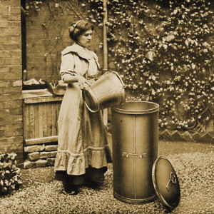 Eine Frau entsorgt müll aus einem kleinen Hauseimer in einen hohen Standeimer.