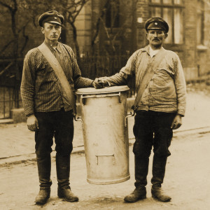 Zwei Männer tragen einen großen Standeimer