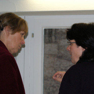 Zwei Teilnehmende stehen vor dem Fenster im Dialog miteinander.