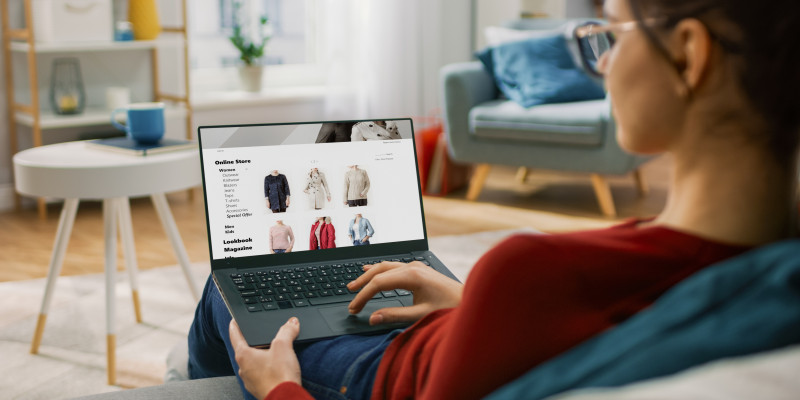 Frau kauft online Kleidung am Laptop ein.