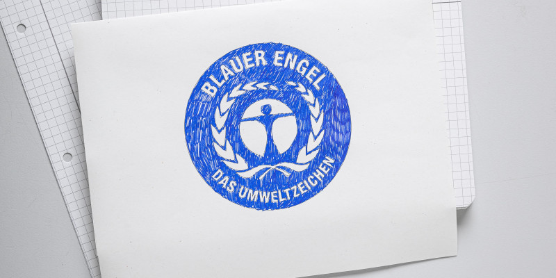 Auf einem Blatt Papier wurde das Umweltzeichen Blauer Engel gemalt.