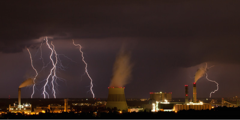 Das Bild zeigt Blitze über einer industriellen Anlage.