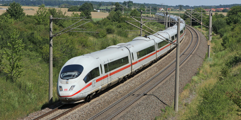 Das Bild zeigt einen fahrenden ICE 3 der Deutschen Bahn AG in ländlicher Umgebung.
