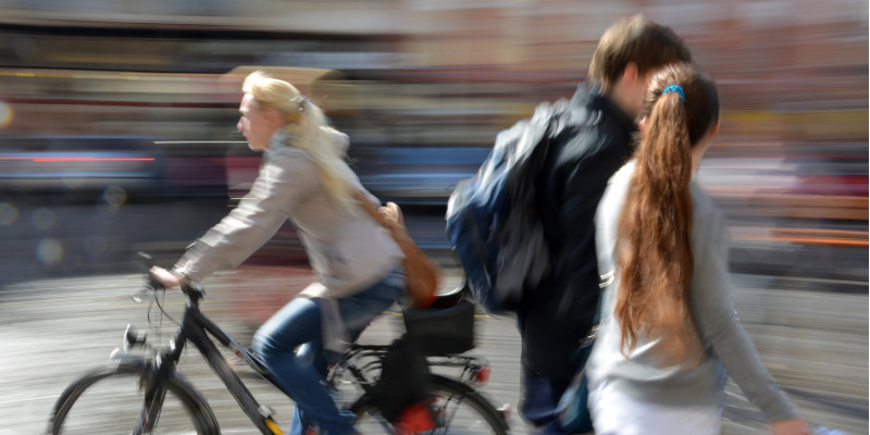 Fußgänger und Radfahrerin in einer Stadt.