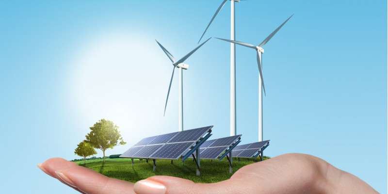 Hand hält Solarfeld und Windräder