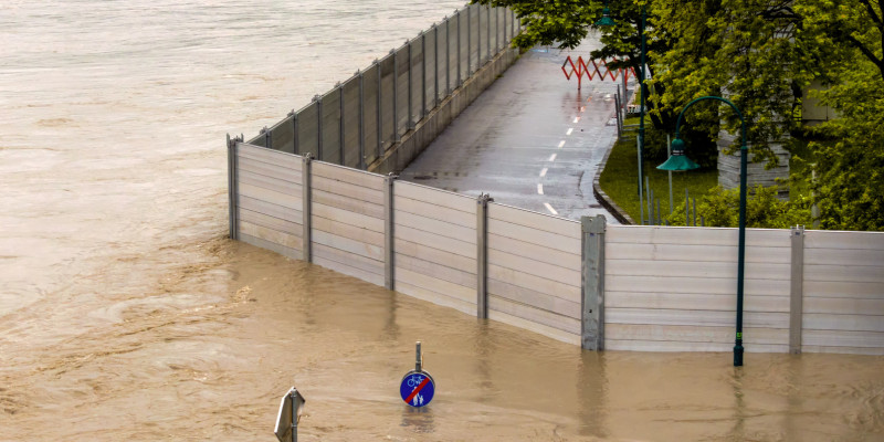 Foto: Eine mobile Hochwasserschutzwand trennt eine überflutete von einer trockenen Straße