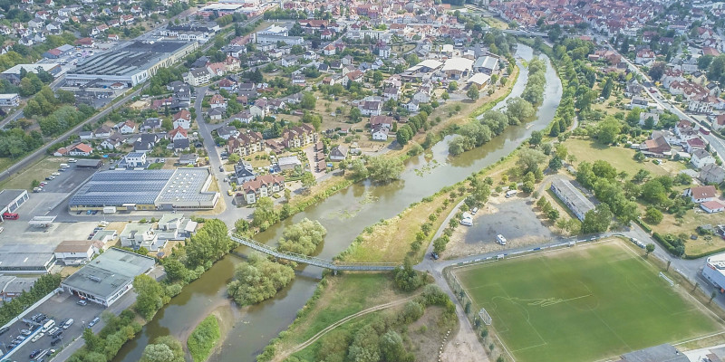 Luftbild auf breites Gewässerbett der Fulda in Rothenburg. Mehrere mit Vegetation bewachsene Inseln liegen im Gewässer. Im Gewässerumfeld liegen bebaute Flächen.