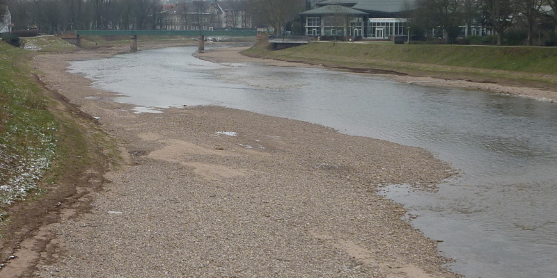 Foto: Ein Abschnitt der Murg kurz nach der Renaturierung. Entlang der Ufer des Gewässers wurde Kies eingebracht, der die eigendynamische Entwicklung des Flusses anregen soll. Eine Kiesbank reicht bis weit in das Gewässer hinein.